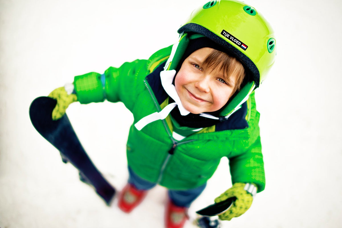 Boy with a black name sticker and Dutch flag on his green ski helmet