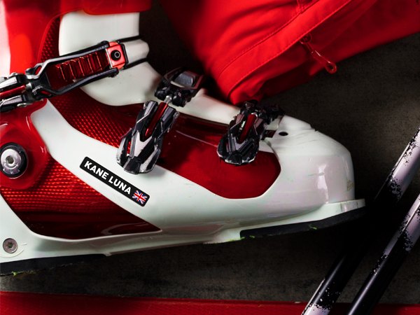 Black name sticker with flag on a red and white ski boot